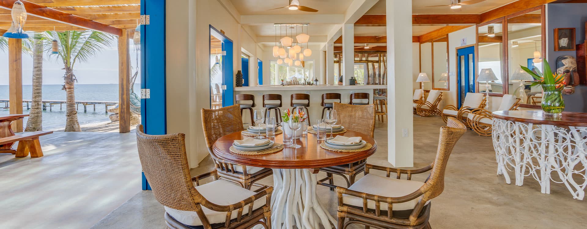 A coastal dining area with a wooden table set for a meal and views of the sea.